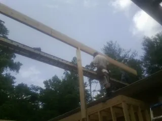 Carpenter setting a ridge beam over a new addition frame — Ice Dam Removal by Roofing Brothers in Lovilia