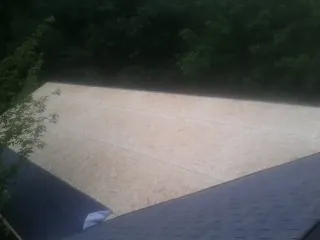 New OSB roof sheathing installed beside an existing shingle roof in Lovilia