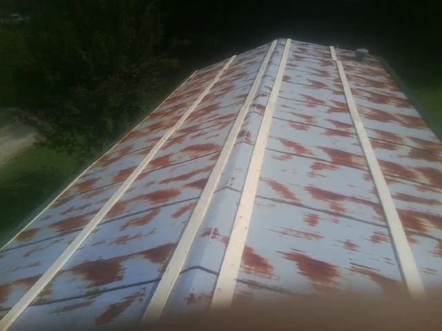 Rusted metal roof panels with new wood purlins before replacement — Storm Damage Roof Repair in Lovilia by Roofing Brothers
