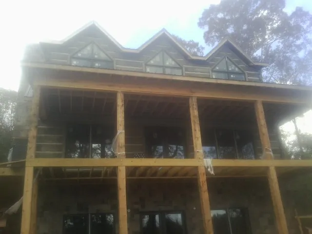 Dormers and porch framing on a large log home under construction — Roof Coating work by our crew in Lovilia