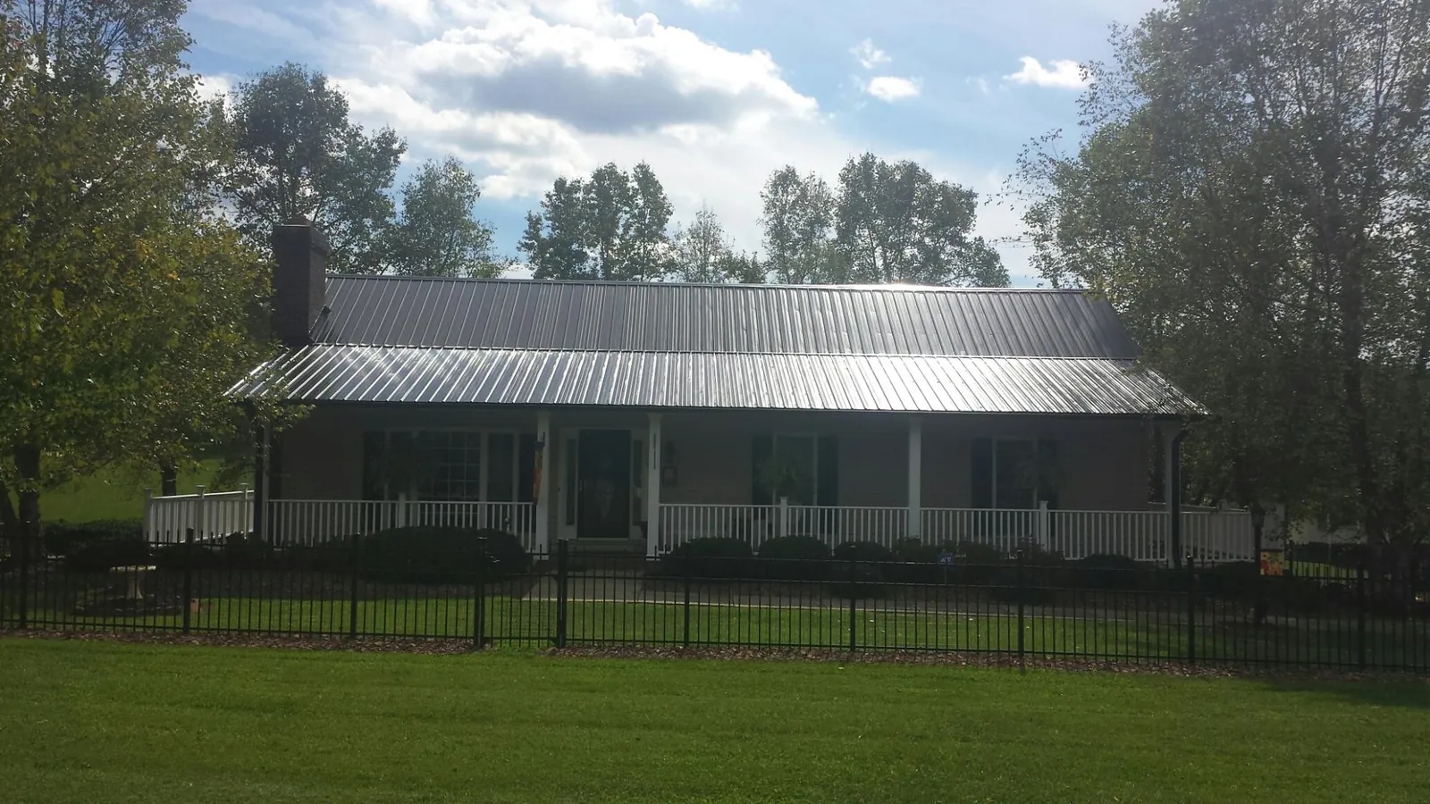 Gray metal roof on a brick ranch with a full width front porch — Gutter Guard Installation work by our crew in Lovilia
