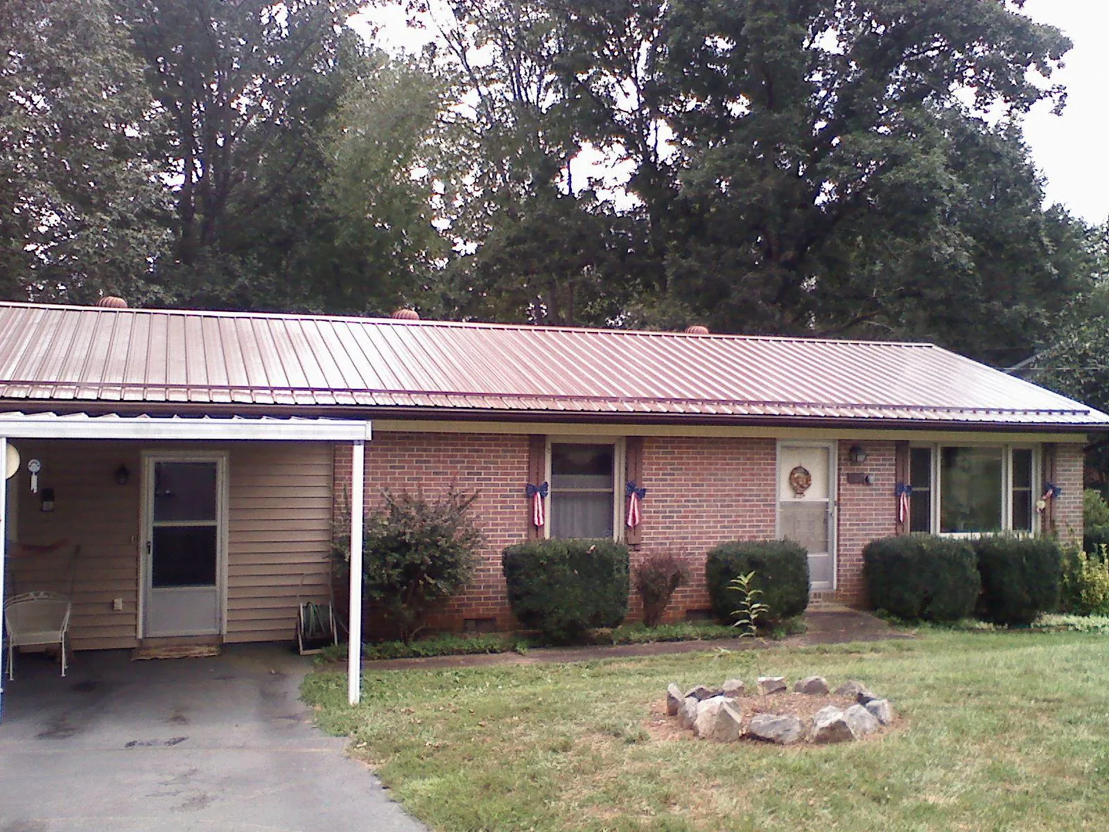 Bronze metal roof and carport on a brick ranch home — Roof Repair work by our crew in Lovilia